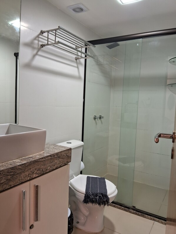 A modern bathroom with a white toilet, a granite countertop, and a glass shower enclosure.