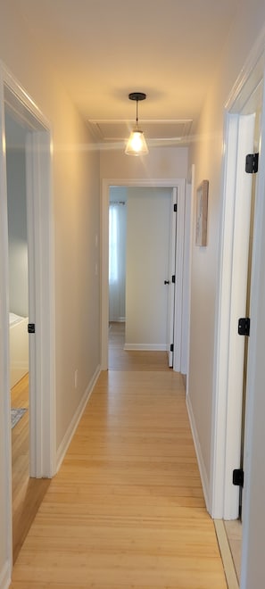 A hallway with wooden flooring, white walls, and a hanging light fixture. - Modern 3BR Home Near Lewes & Beaches (Milton)