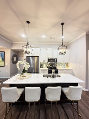 A modern kitchen with a central island, stainless steel appliances, and pendant lighting.