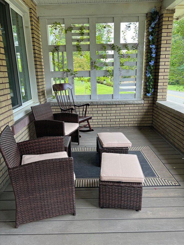 Eine überdachte Veranda mit Korbmöbeln und Blick auf eine grüne Landschaft.
