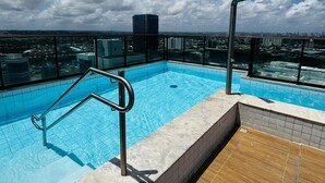 A rooftop pool with clear blue water, surrounded by a wooden deck and metal railings. - Apartment 350 meters from the shopping mall (Boa Viagem Recife)