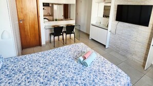 A bedroom with a bed, a desk, and a kitchenette. - Apartment 350 meters from the shopping mall (Boa Viagem Recife)