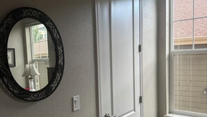 A room with a white door, a window with blinds, and a wall-mounted mirror. - Relaxing Arvada Escape Between Golden & Boulder (Arvada)