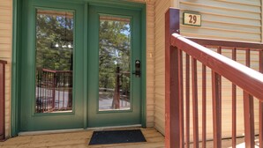 Une porte verte portant le numéro 29, un porche en bois et une balustrade rouge.