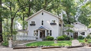 A two-story house with a front porch, a covered entryway, and a stone foundation. - Lakefront Estate w/ Beach & Boat • Sleeps 30 • Near IN Dunes National Park (Valparaiso)