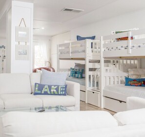 Ein Zimmer mit Etagenbetten, einem weißen Sofa und einem Glastisch.
