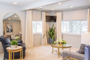 A modern living room with a leather sofa, a round glass coffee table, and a potted plant.