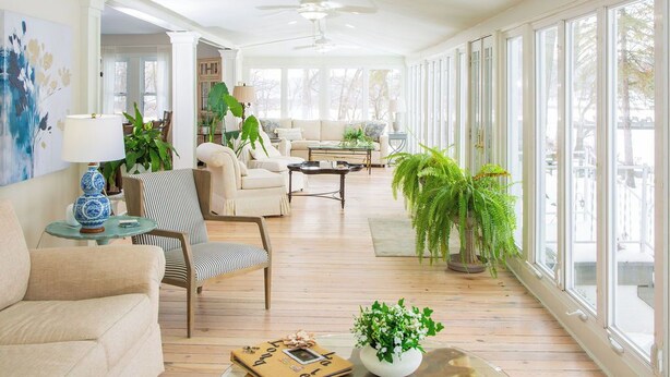A spacious living room with a high ceiling, large windows, and a variety of seating options including a sofa, armchairs, and a coffee table. - Lakefront Estate w/ Beach & Boat • Sleeps 30 • Near IN Dunes National Park (Valparaiso)