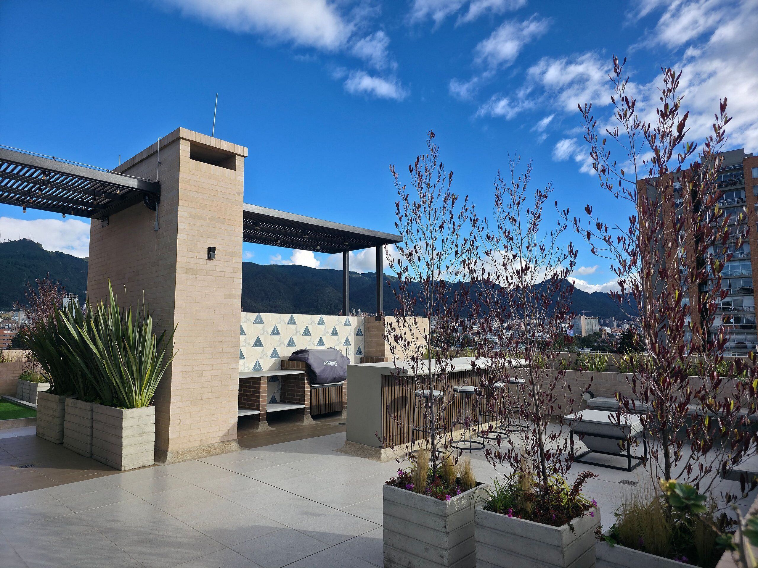 An outdoor patio with seating, a barbecue grill, and potted plants.