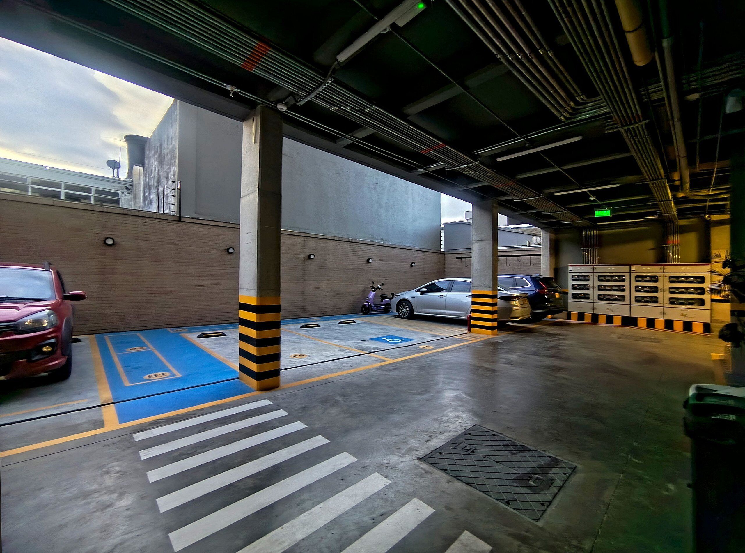 Een parkeergarage met betonnen pilaren, een blauwe parkeerplaats en een voetgangersoversteek.