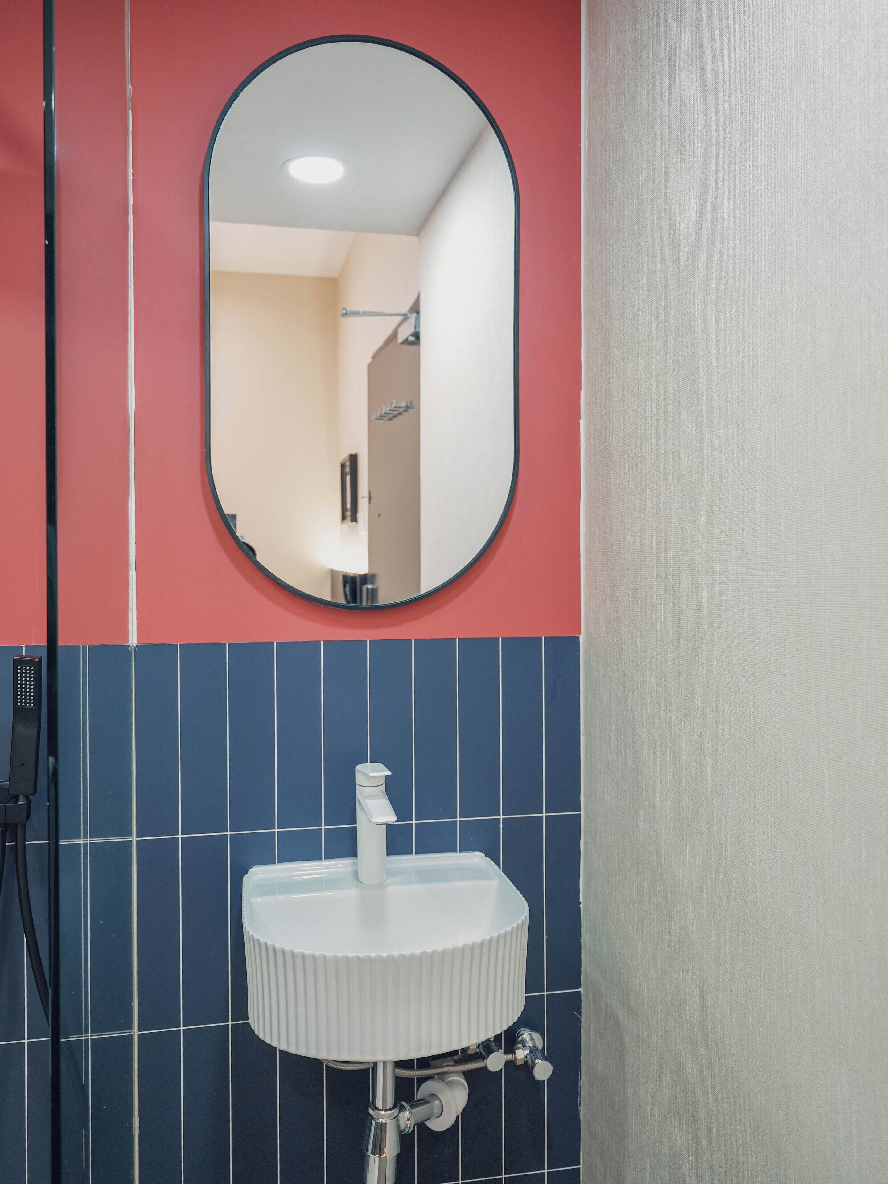 A bathroom with a white sink, a mirror, and blue-tiled walls.