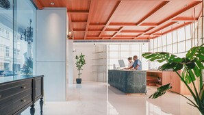 Een moderne receptie met houten plafond, een receptiebalie, een plant in pot en uitzicht door een glazen wand.