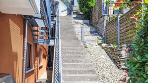 A narrow concrete staircase leading up to a building with a metal railing on one side and a stone wall on the other. - Residenza Solaria Endless View by Interhome (Gordola)