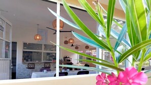 A modern interior with a dining area, pendant lighting, and a view of the outside. - Family Room. Quinta yaaxbe (Homun)