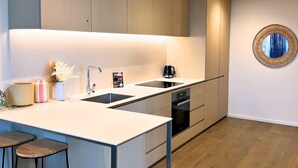 A modern kitchen with a central island, built-in appliances, and a round mirror on the wall.