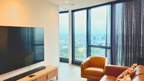 A modern living room with a large flat-screen TV, leather sofa, and a wooden coffee table.