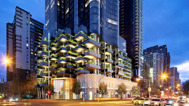 A modern high-rise building with multiple balconies, a prominent entrance, and a street view with traffic.