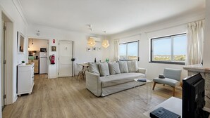 A spacious living area with a sofa, a dining table, and a kitchen in the background.