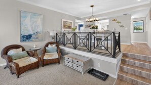 A spacious living area with a high ceiling, a staircase, and a view of the kitchen. - Coastal Lakehouse Condo on Siesta Key Public Beach (Siesta Key)