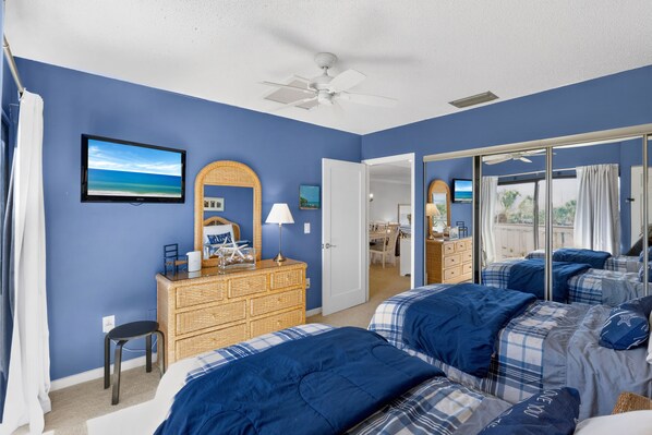 A bedroom with a large bed, a dresser, a television, and a sliding glass door leading to a balcony. - Coastal Lakehouse Condo on Siesta Key Public Beach (Siesta Key)