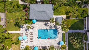An aerial view of a resort with a swimming pool, sun loungers, and palm trees. - Coastal Lakehouse Condo on Siesta Key Public Beach (Siesta Key)