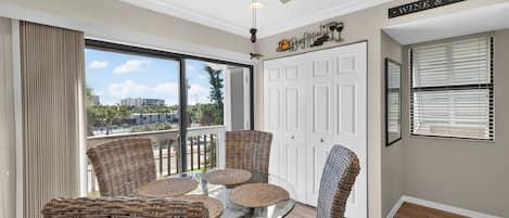 Un balcon avec des fauteuils en osier, une table en verre et un ventilateur de plafond.