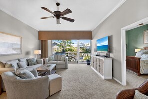 A living room with a sofa set, a coffee table, a TV, and a ceiling fan. - Coastal Lakehouse Condo on Siesta Key Public Beach (Siesta Key)
