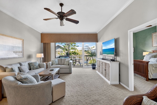 A living room with a sofa set, a coffee table, a TV, and a ceiling fan.