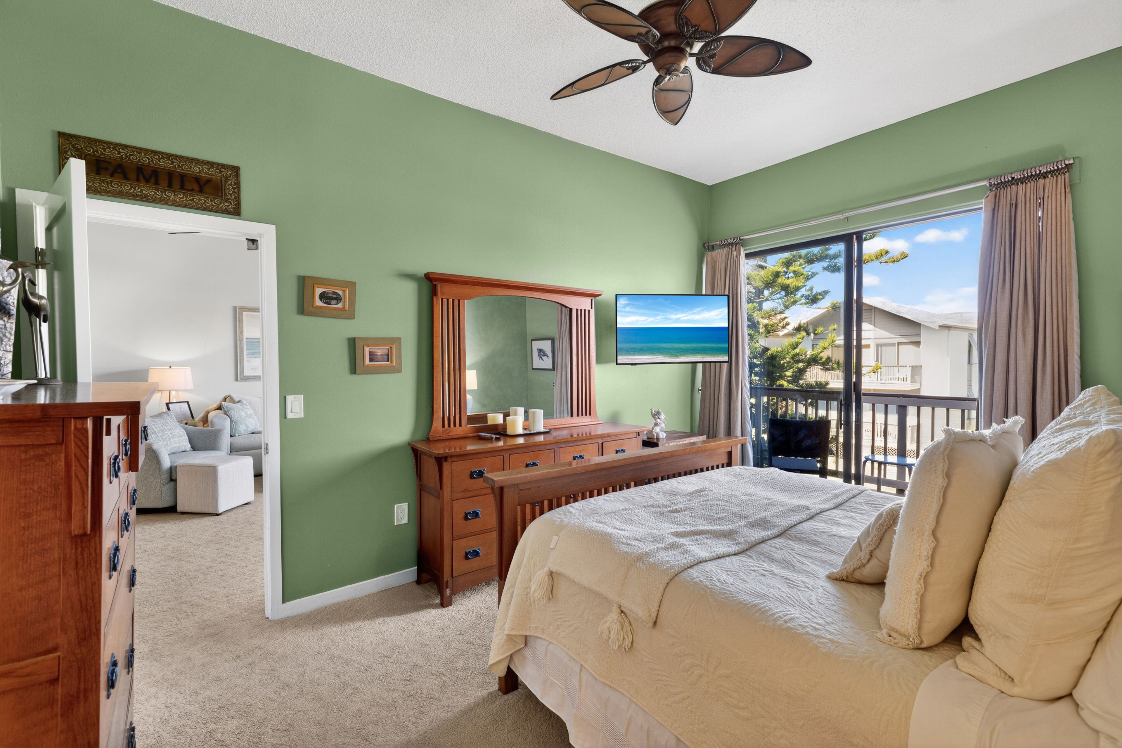 A bedroom with a bed, dresser, mirror, and a television.
