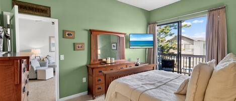 A bedroom with a bed, dresser, mirror, and a television.
