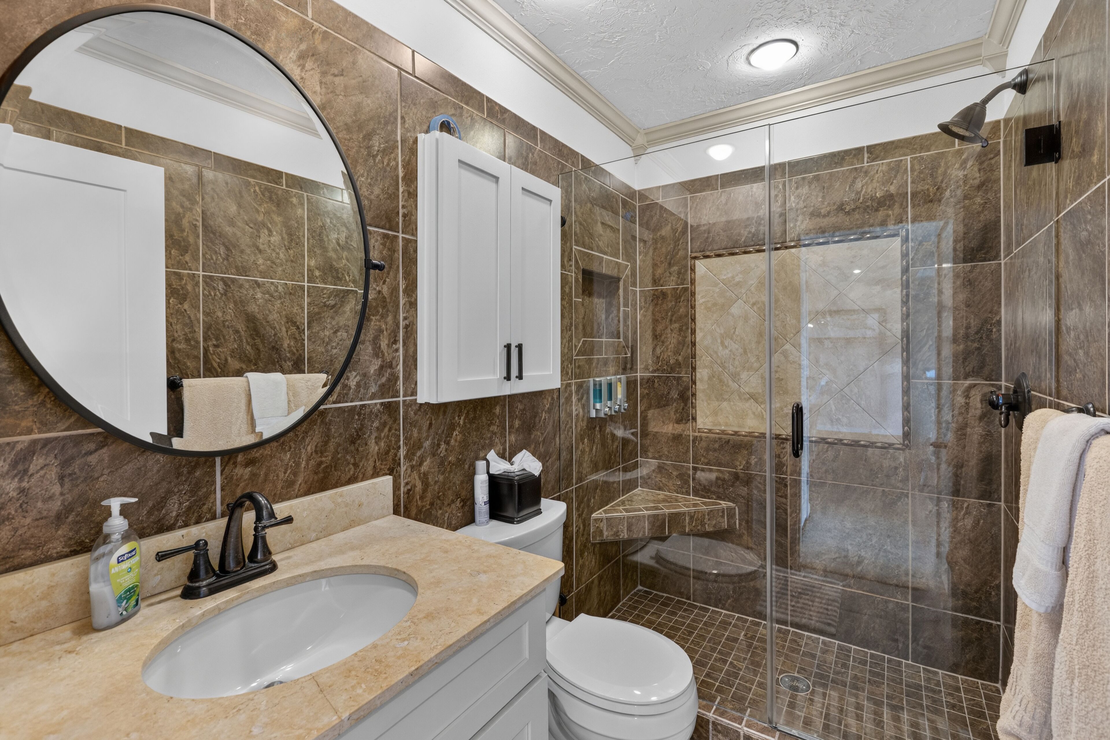 Une salle de bain équipée d’un lavabo, d’un miroir, de toilettes et d’un espace douche.