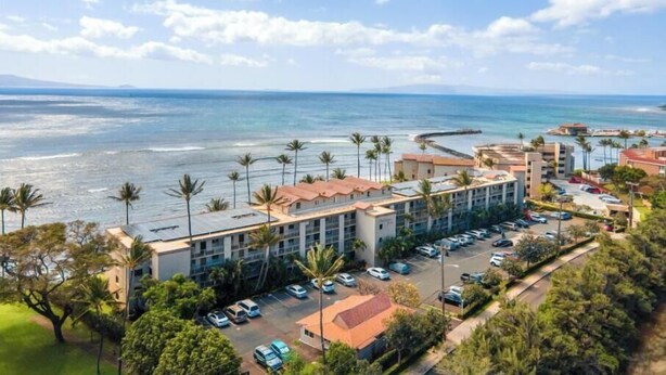 Un hotel frente al mar con estacionamiento, vistas al océano y palmeras.