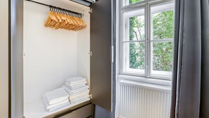 Une chambre avec un placard, une fenêtre donnant sur des arbres et un radiateur.