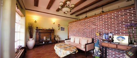 A cozy living room with a brick wall, wooden beams, a sofa, a coffee table, and a fireplace.