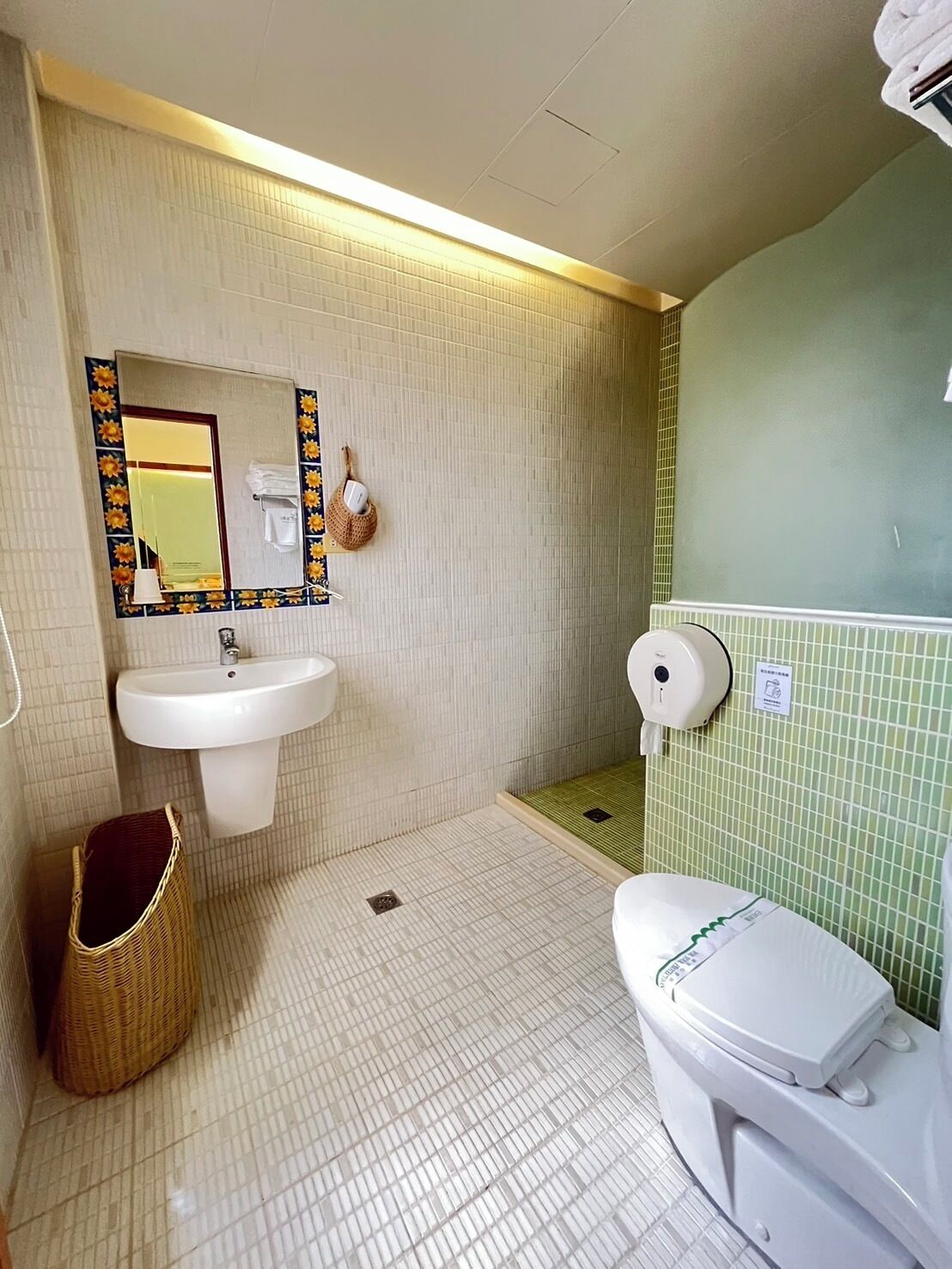 A bathroom with a sink, mirror, toilet, and a trash bin.
