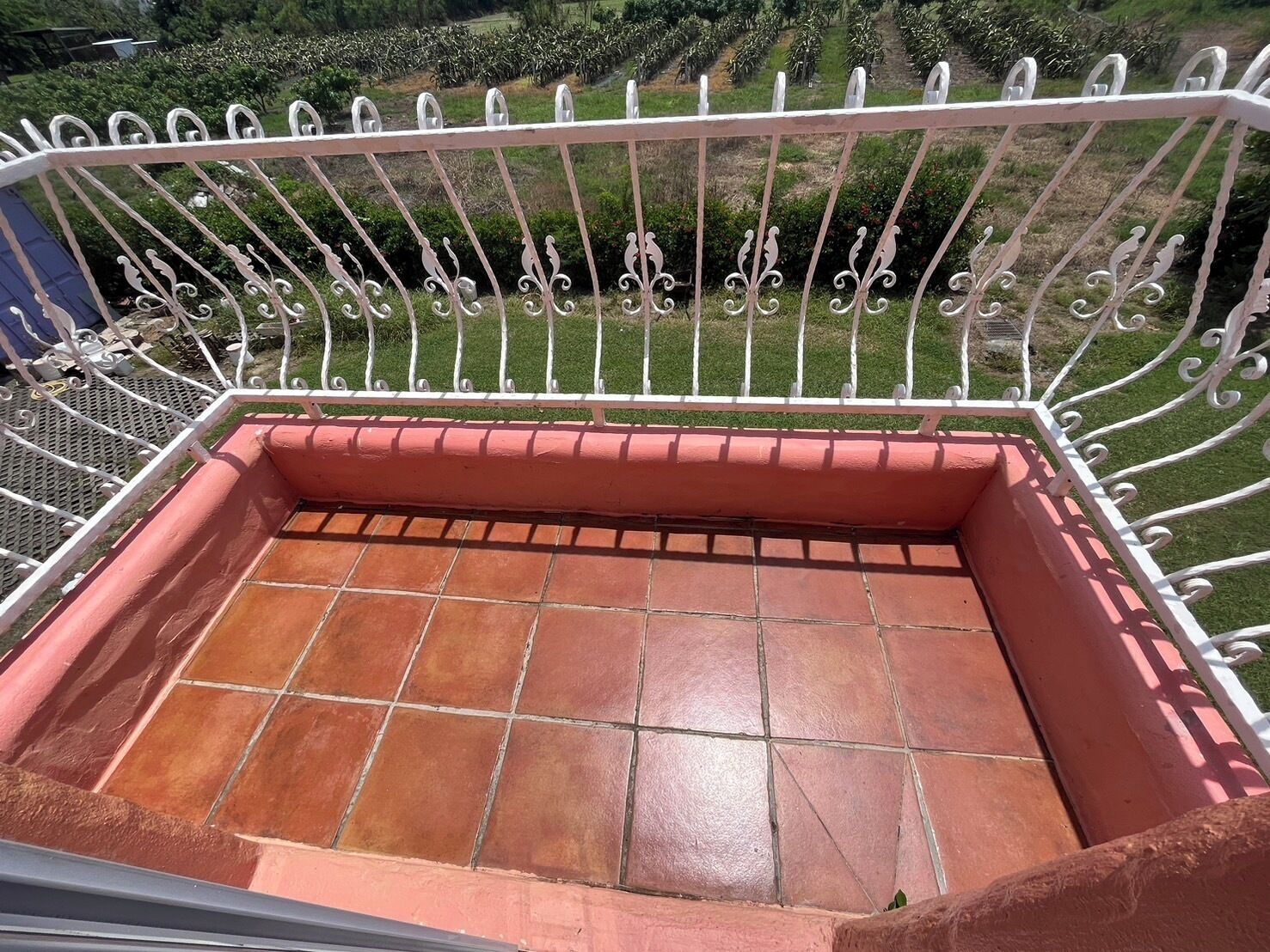 Een balkon met betegelde vloer en een witte metalen reling.