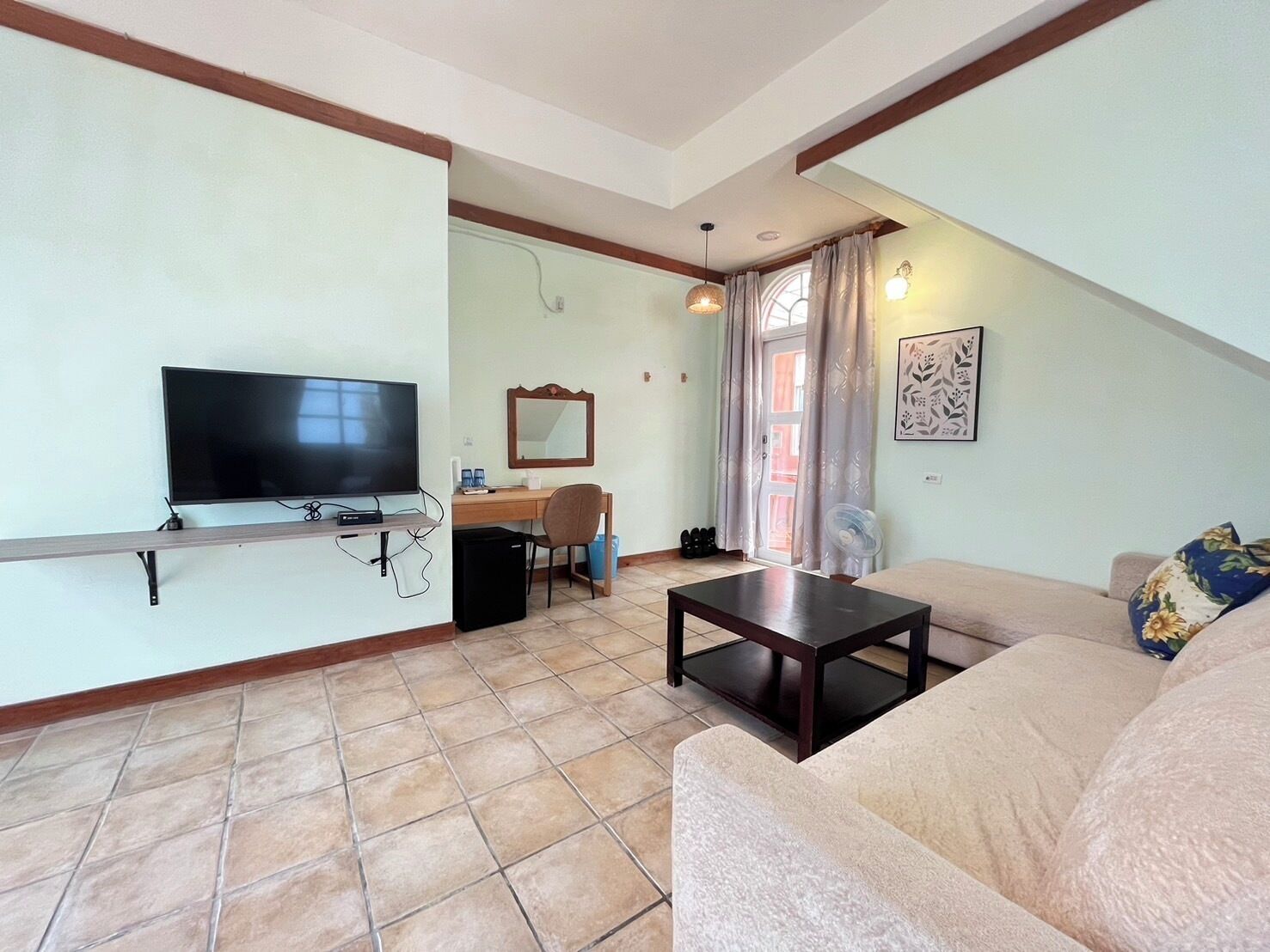 A living room with a TV, a desk, a chair, a sofa, and a small table.