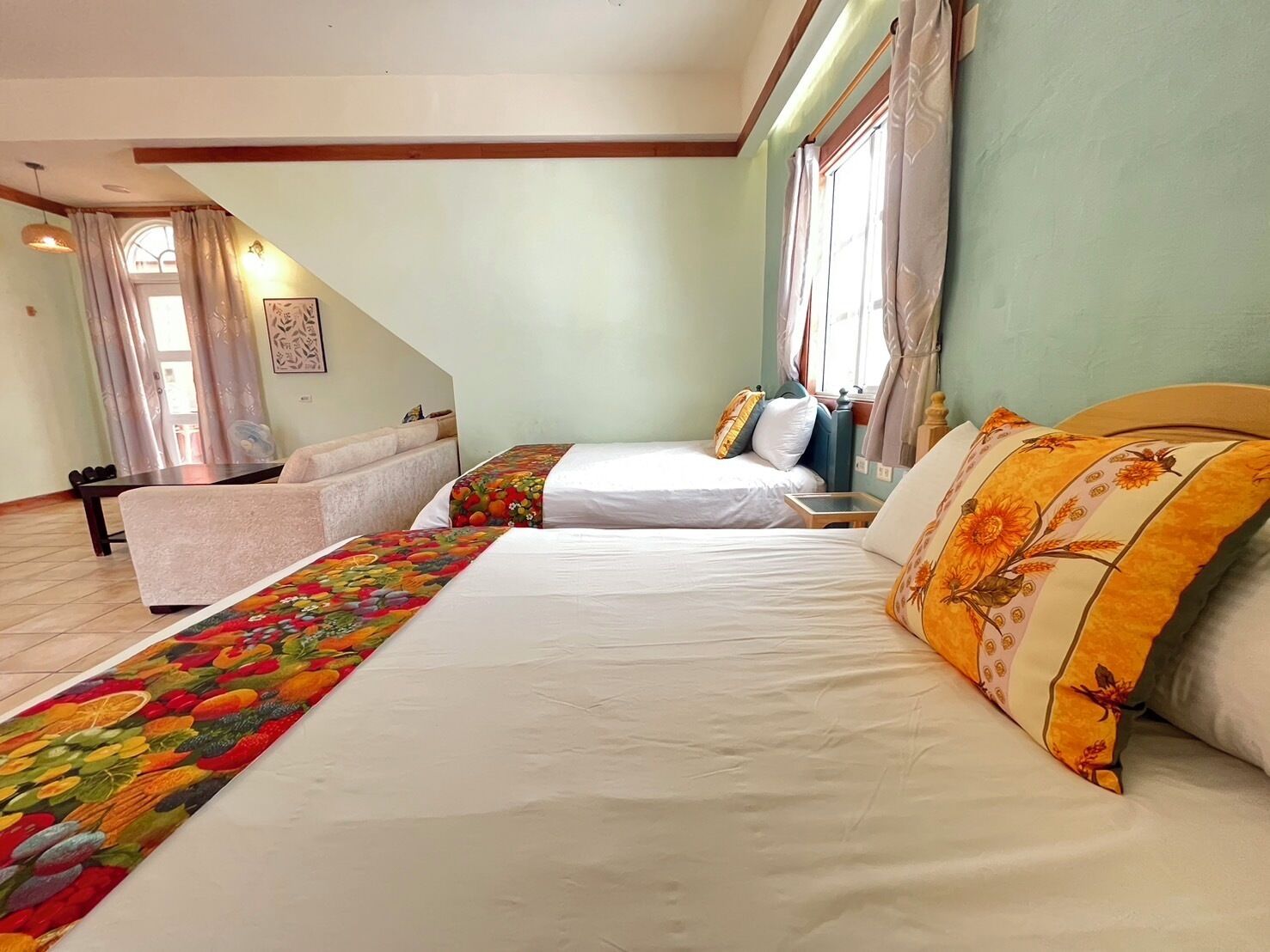 Une chambre avec deux lits, un canapé, une table à manger et une fenêtre avec des rideaux.