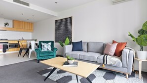 A modern living room with a sofa, coffee table, and a dining area with chairs and a table.