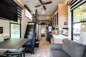 Cocina compacta con comedor, una escalera y un rincón de estar con vistas al exterior.