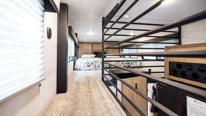 A narrow hallway with bunk beds, a kitchenette, and a window with blinds. - Tiny RV Escape with Stunning Lake Views, AC, WiFi (Nevis)