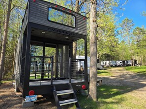 A black recreational vehicle with a ramp and a nameplate reading 'TIMBERWOLF'. - Tiny RV with amazing lake view! (Nevis)