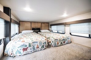 A compact RV interior with two beds, a kitchenette, and a small bathroom. - Tiny RV with amazing lake view! (Nevis)