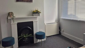 Et værelse med pejs, radiator og et vindue med skodder.