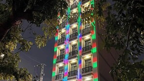 A building with colorful vertical LED lights, a sign reading "KHÃCH SAN ANH THÃO", and two buses parked in front. - Anh Thao Hotel Quy Nhơn (Quy Nhon Nam)
