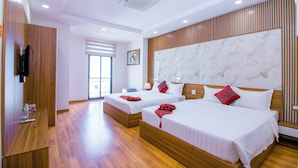 A hotel room with two beds, wooden flooring, a large marble headboard, and a television on a wooden shelf. - Anh Thao Hotel Quy Nhơn (Quy Nhon Nam)