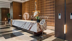 A reception area with a marble counter, wooden panel wall, and potted plants. - Staya Antasari by Kozystay - Cilandak (Jakarta)