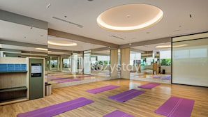 A spacious room with wooden flooring, multiple purple yoga mats, a water dispenser, and large mirrors on the walls. - Staya Antasari by Kozystay - Cilandak (Jakarta)