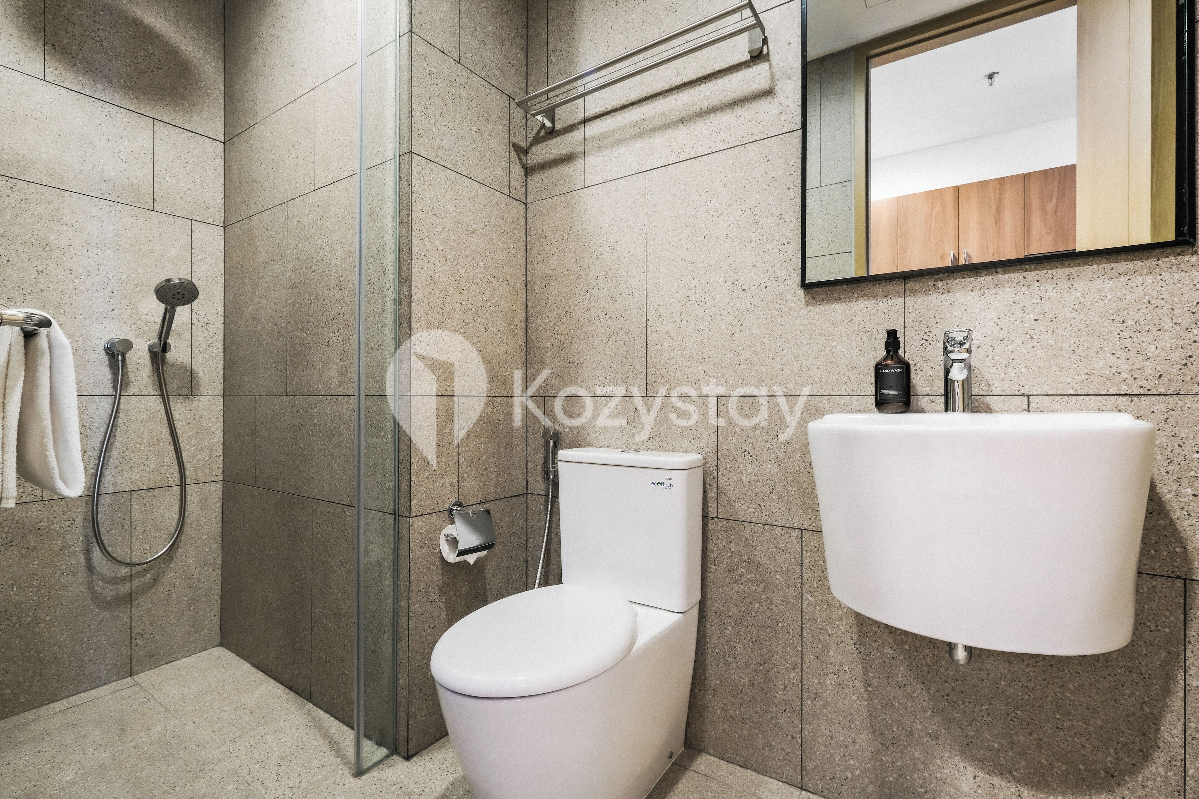 Un baño moderno con cabina de ducha de vidrio, inodoro y lavamanos.