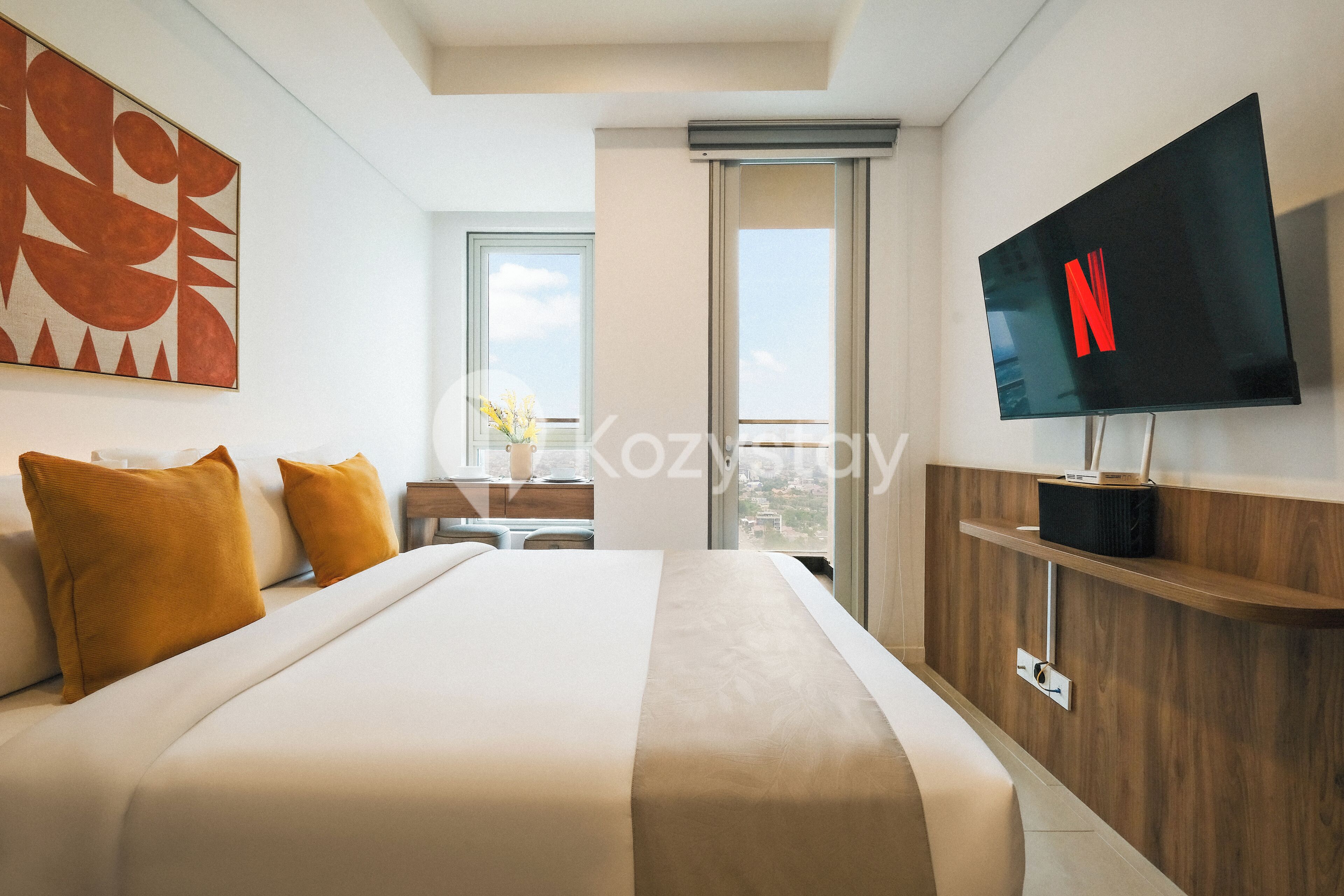 Un hotel moderno con una cama grande, un televisor montado en la pared y vista a la ciudad por la ventana.